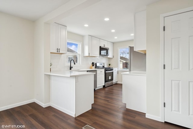 kitchen featuring tasteful backsplash, white cabinetry, stainless steel appliances, and dark wood-type flooring