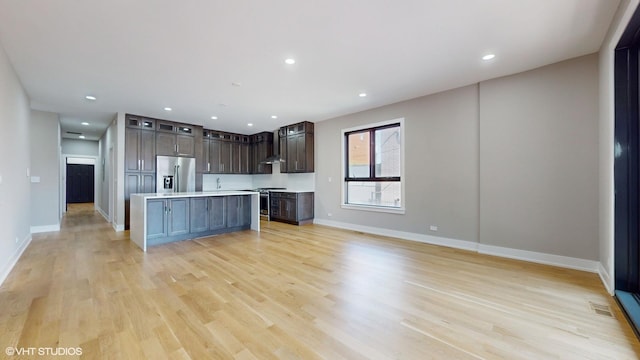 kitchen with a center island, dark brown cabinetry, appliances with stainless steel finishes, and light hardwood / wood-style flooring