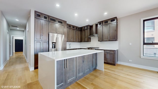 kitchen featuring light hardwood / wood-style floors, a kitchen island, high quality fridge, and wall chimney exhaust hood