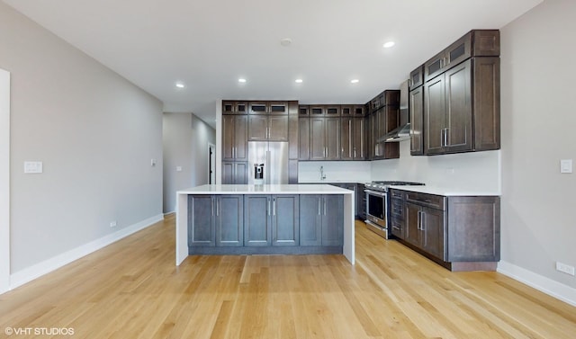 kitchen with dark brown cabinets, a kitchen island, stainless steel appliances, and light wood-type flooring