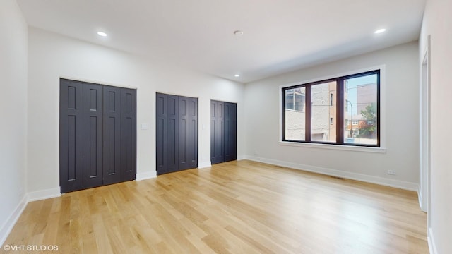 unfurnished bedroom featuring two closets and light hardwood / wood-style flooring