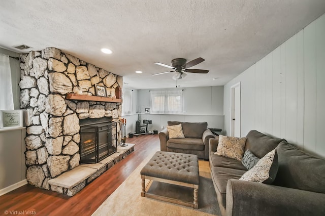 living room featuring a fireplace, hardwood / wood-style floors, a textured ceiling, and ceiling fan