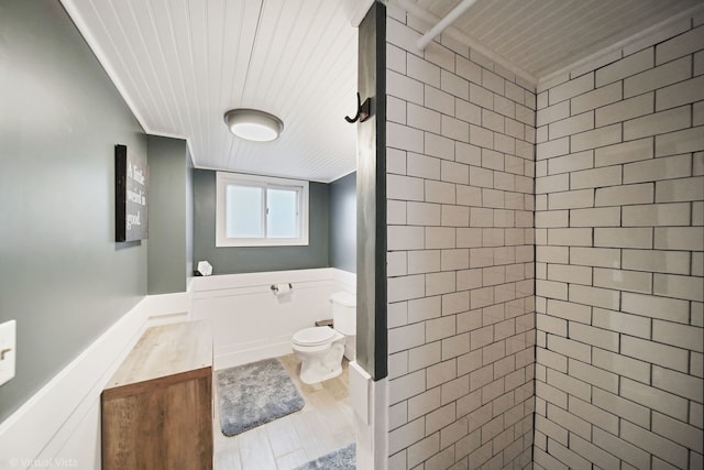 bathroom with a tile shower, vanity, wood-type flooring, and toilet