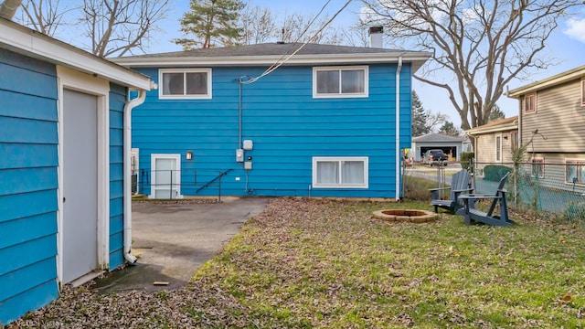 rear view of house with a yard and an outdoor fire pit