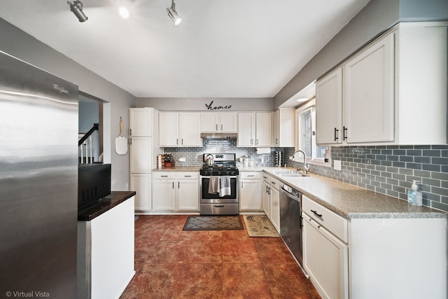 kitchen with white cabinets, sink, dark tile patterned floors, appliances with stainless steel finishes, and tasteful backsplash