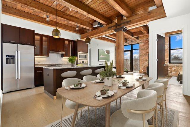 dining space with beamed ceiling, brick wall, light hardwood / wood-style floors, and wooden ceiling