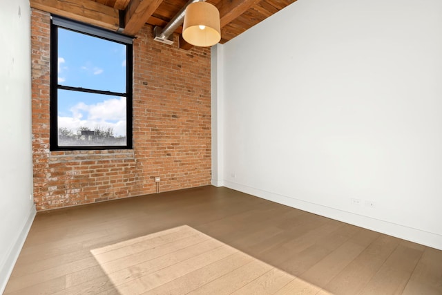 empty room with beamed ceiling, brick wall, wooden ceiling, and wood-type flooring