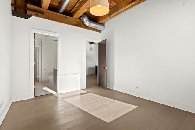 unfurnished bedroom with connected bathroom, dark hardwood / wood-style floors, beam ceiling, and wood ceiling