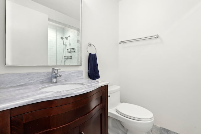 bathroom featuring tiled shower, toilet, and vanity