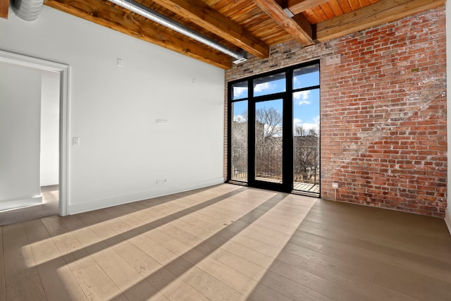 empty room featuring wood ceiling, brick wall, light hardwood / wood-style flooring, and beamed ceiling