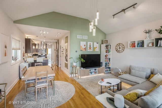 living room with track lighting, high vaulted ceiling, and light hardwood / wood-style flooring