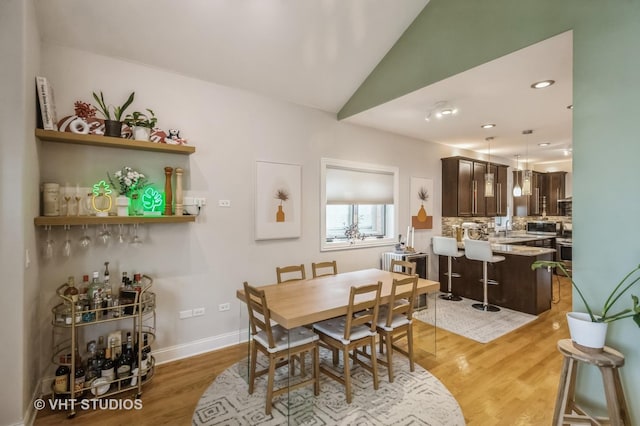 dining space with hardwood / wood-style floors, vaulted ceiling, and sink