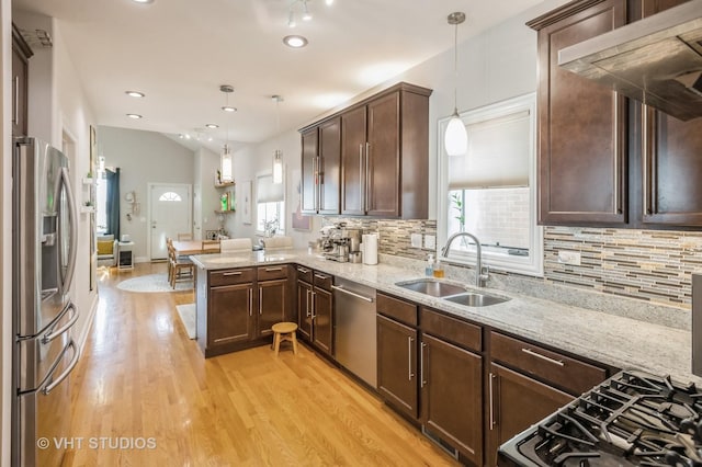 kitchen featuring sink, kitchen peninsula, plenty of natural light, decorative light fixtures, and appliances with stainless steel finishes