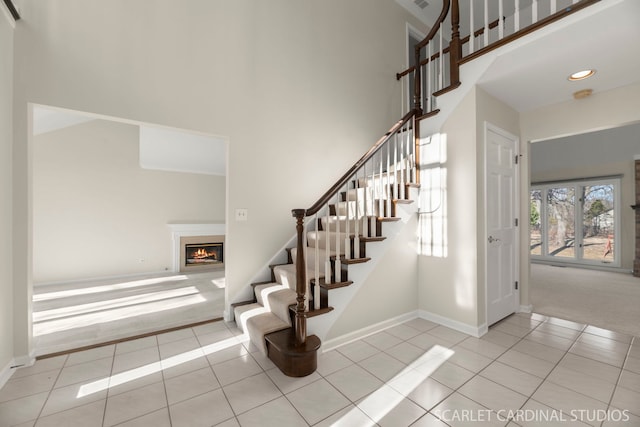 staircase with tile patterned flooring and a high ceiling