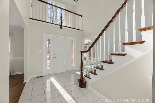 entryway with a towering ceiling, a healthy amount of sunlight, and light tile patterned floors