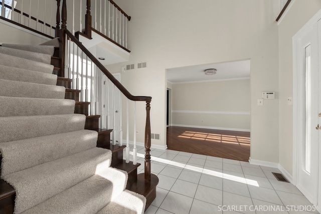 staircase with tile patterned flooring and a high ceiling