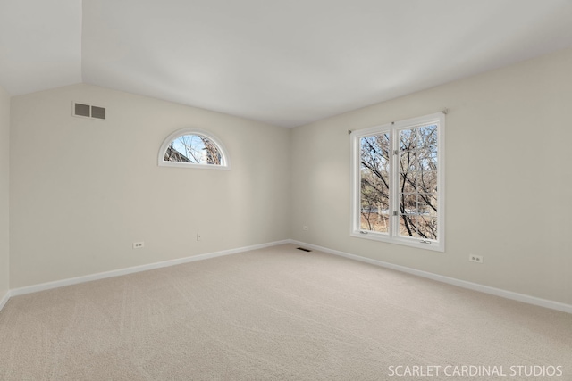 carpeted empty room with vaulted ceiling