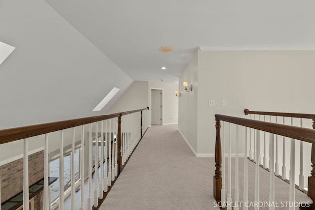 hall featuring lofted ceiling with skylight, light colored carpet, and crown molding