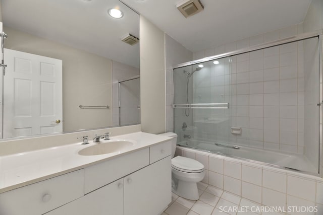 full bathroom with vanity, bath / shower combo with glass door, tile patterned floors, and toilet