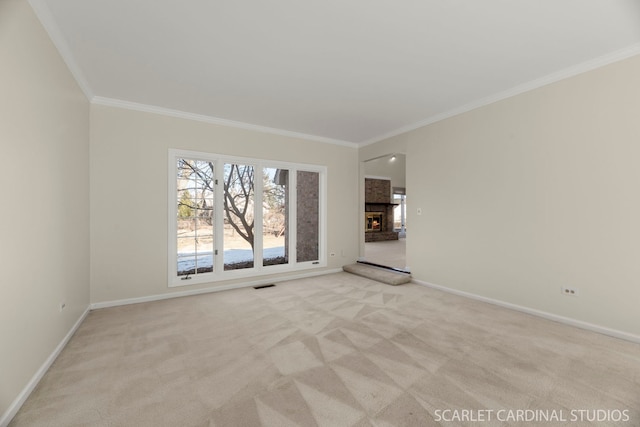 carpeted spare room featuring ornamental molding and a fireplace