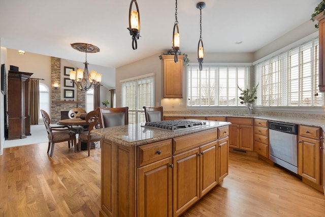 kitchen with decorative light fixtures, a kitchen island, a notable chandelier, light hardwood / wood-style floors, and stainless steel appliances