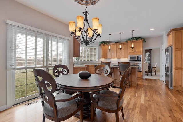 dining room with plenty of natural light, light wood-type flooring, and an inviting chandelier