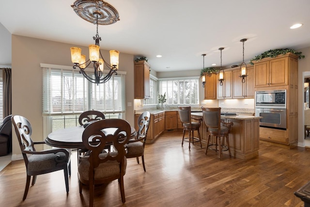 dining space featuring sink, dark hardwood / wood-style flooring, a healthy amount of sunlight, and an inviting chandelier