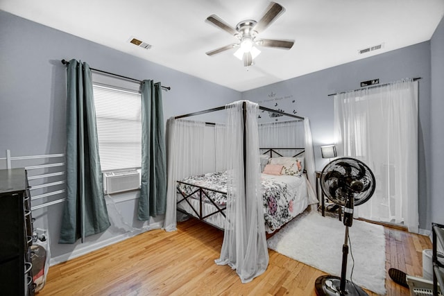 bedroom with ceiling fan, cooling unit, and hardwood / wood-style flooring