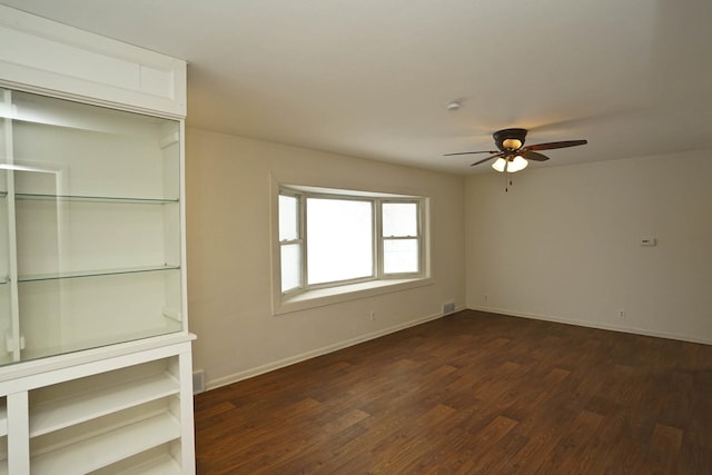 empty room with ceiling fan and dark wood-type flooring