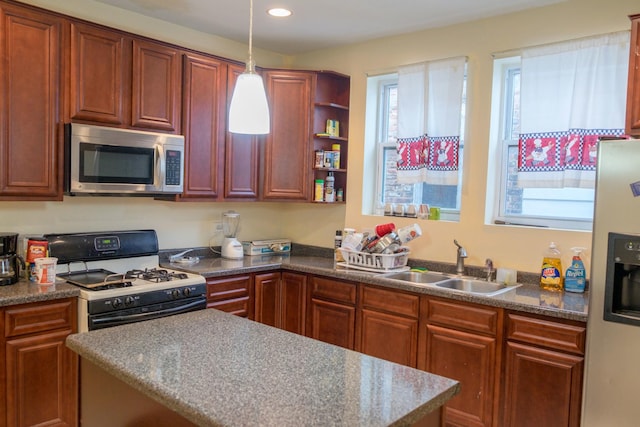 kitchen featuring white appliances, decorative light fixtures, a wealth of natural light, and sink