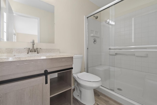 bathroom featuring hardwood / wood-style floors, vanity, a shower with shower door, and toilet