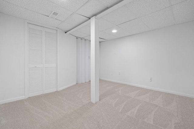 basement featuring light colored carpet and a drop ceiling