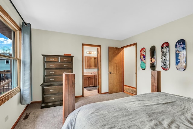 bedroom with ensuite bath, sink, and light colored carpet