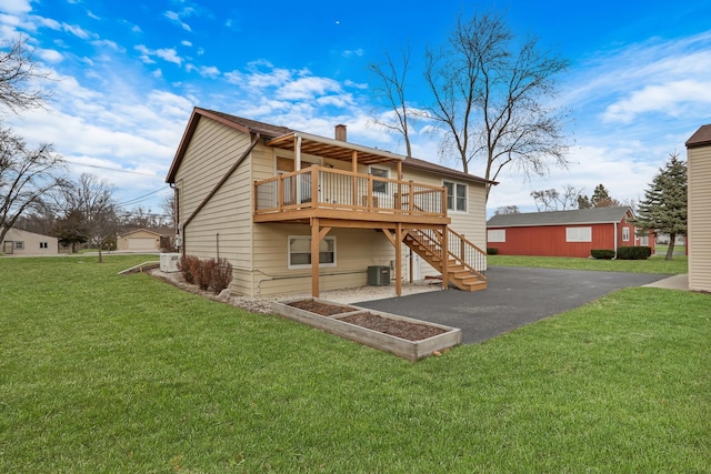 rear view of house featuring a wooden deck, cooling unit, and a lawn