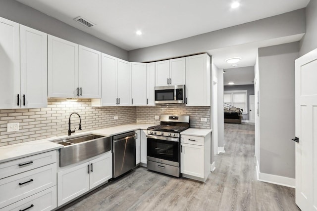 kitchen featuring backsplash, sink, white cabinetry, and stainless steel appliances