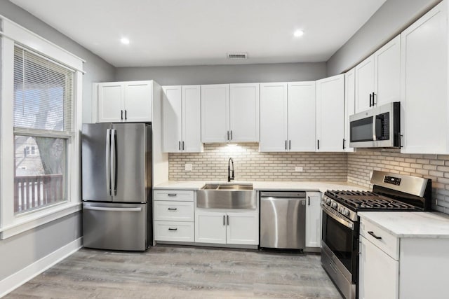 kitchen featuring white cabinetry, sink, light hardwood / wood-style flooring, and appliances with stainless steel finishes