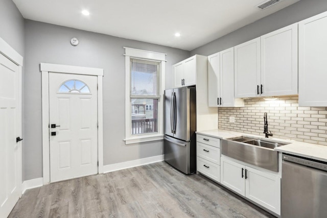 kitchen featuring sink, stainless steel appliances, white cabinetry, and light stone counters