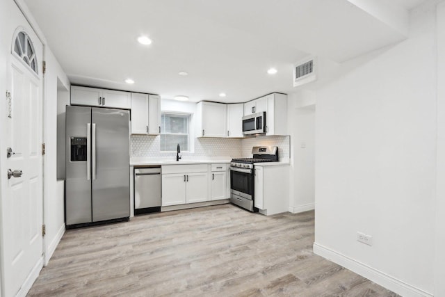 kitchen with sink, white cabinets, stainless steel appliances, and light wood-type flooring