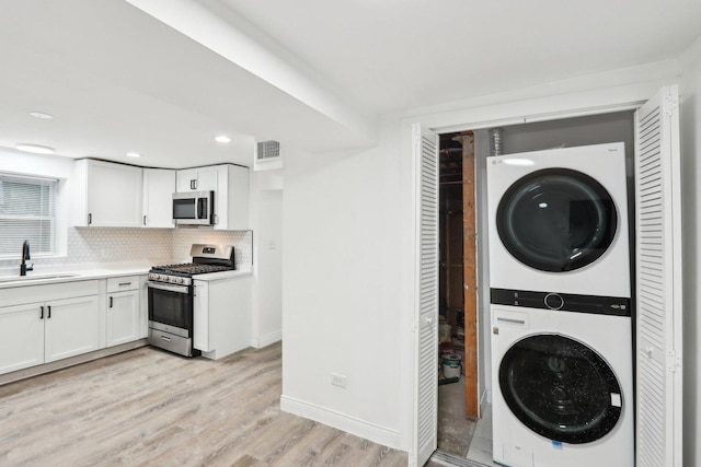 laundry room featuring light wood-type flooring, stacked washing maching and dryer, and sink