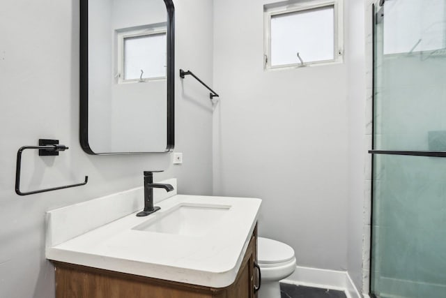 bathroom featuring vanity, toilet, and a shower with shower door