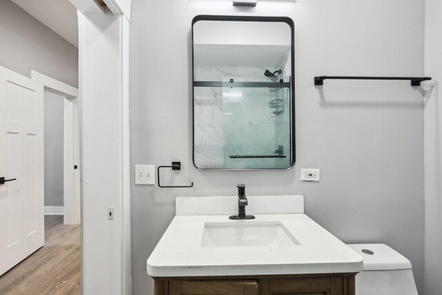 bathroom with hardwood / wood-style floors, vanity, toilet, and an enclosed shower