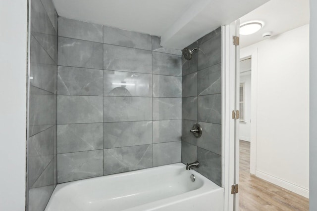 bathroom with hardwood / wood-style floors and tiled shower / bath