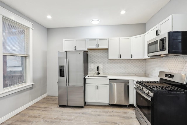 kitchen featuring white cabinetry, sink, appliances with stainless steel finishes, and light hardwood / wood-style flooring