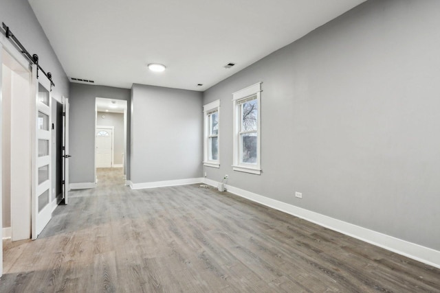 empty room with a barn door and hardwood / wood-style flooring