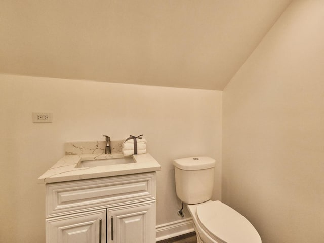 bathroom with vanity, toilet, and lofted ceiling