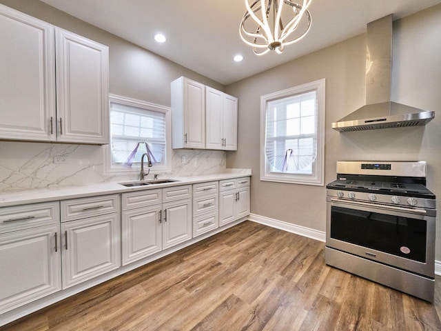 kitchen with stainless steel range, sink, wall chimney range hood, white cabinets, and light hardwood / wood-style floors