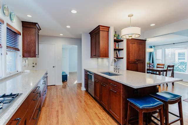 kitchen featuring light hardwood / wood-style floors, stainless steel appliances, hanging light fixtures, light stone counters, and sink