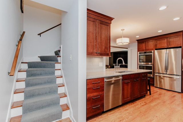 kitchen with stainless steel appliances, sink, decorative light fixtures, decorative backsplash, and light stone countertops