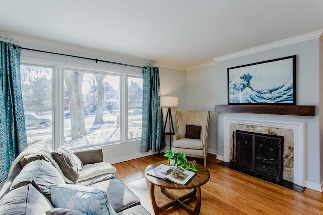 living room with light hardwood / wood-style floors, crown molding, and a high end fireplace