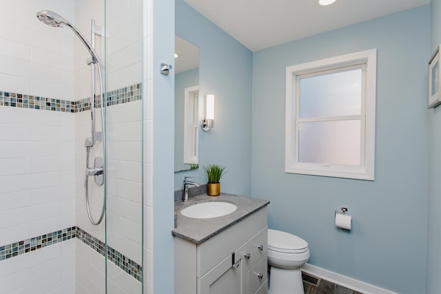 bathroom with a tile shower, vanity, and toilet